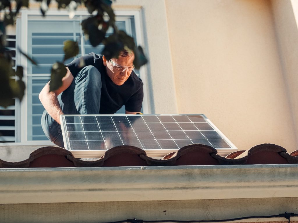 Person installing a solar panel on a rooftop for sustainable energy