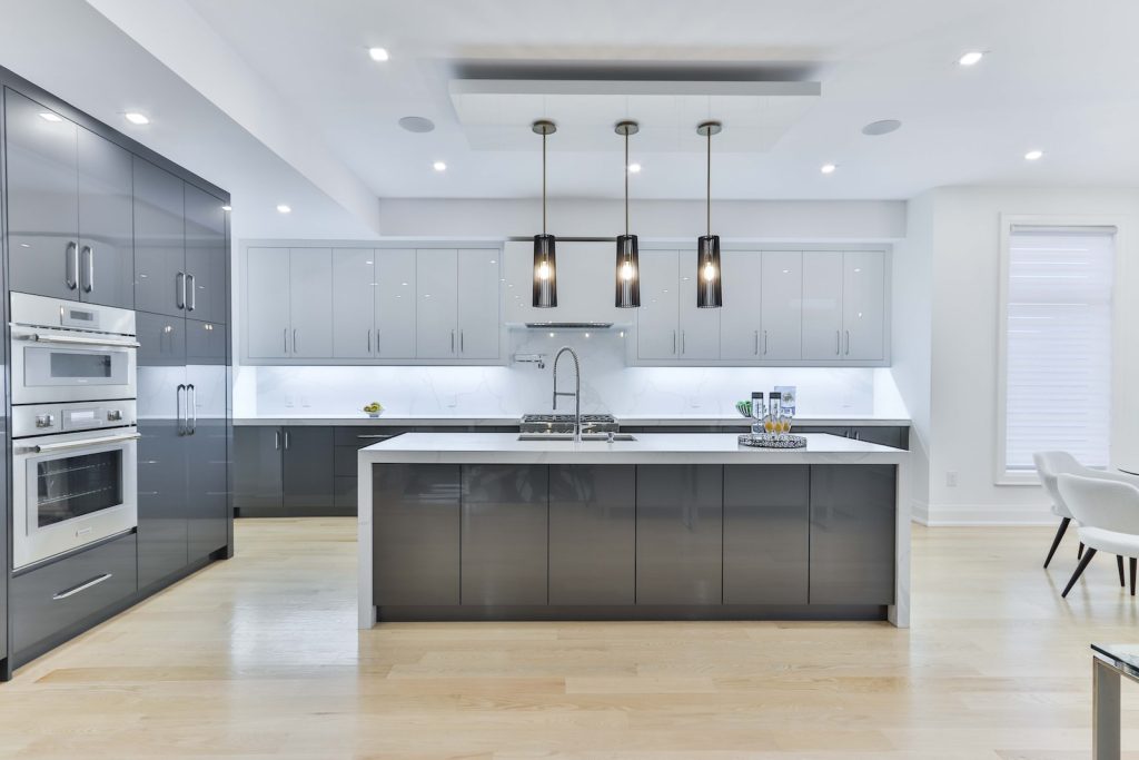 Modern kitchen with sleek gray cabinets, island, pendant lights, and stainless steel appliances