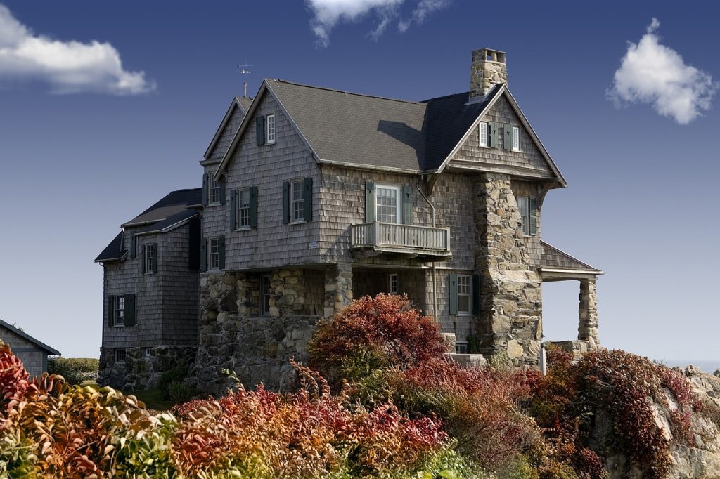 Stone cottage with a wooden facade surrounded by colourful autumn foliage under a clear blue sky
