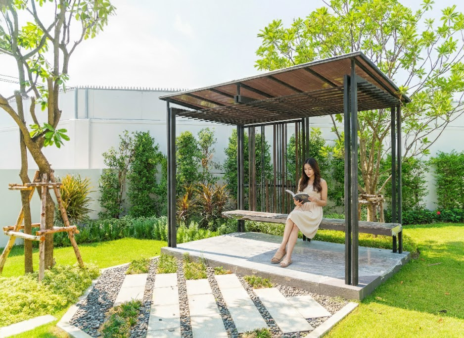 A woman sitting on a bench surrounded by vibrant flowers in a serene garden setting